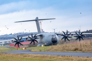 Large military aircraft preparing for takeoff with birds in the background.