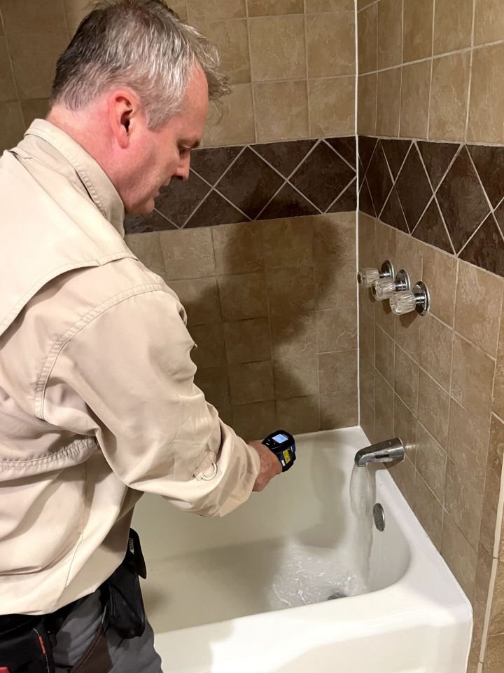 Home inspector evaluating a bathtub and plumbing fixture during a residential inspection in Sparta, Tennessee