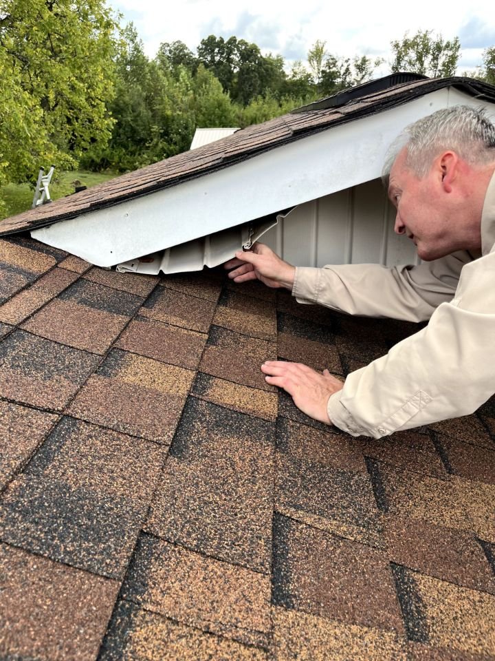 John Griffith inspecting roof shingles and flashing during a home inspection in Gainesboro, Tennessee.