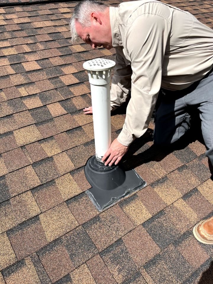John Griffith examining a roof vent and surrounding shingles during a home inspection in Carthage, Tennessee